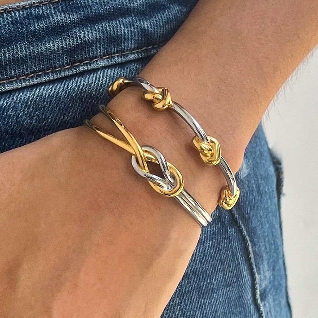 Wrist wearing two-tone gold and silver Entwined Knot cuff bracelets