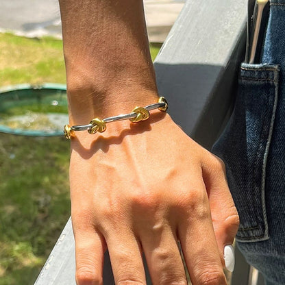 Hand with rings wearing the gold and silver Entwined Knot cuff