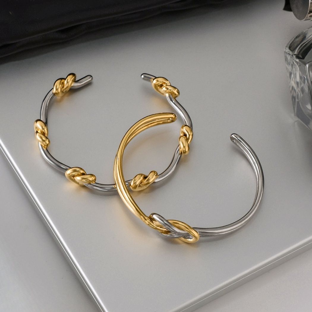 Two Entwined Knot cuff bracelets displayed on a stone