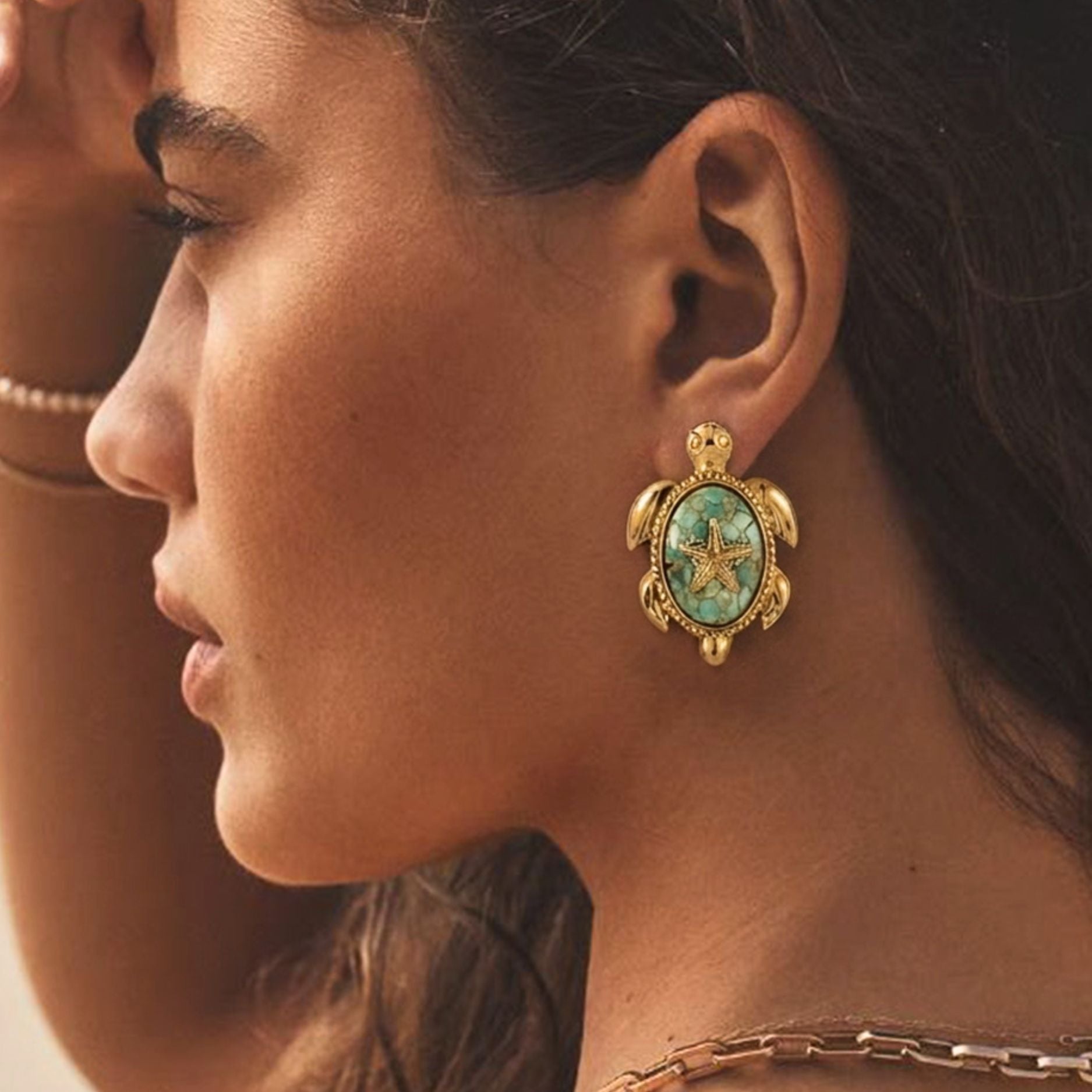 Profile view of a model wearing an 18K gold plated stainless steel sea turtle stud earring featuring a textured turquoise stone inlay shell and central golden starfish detail.