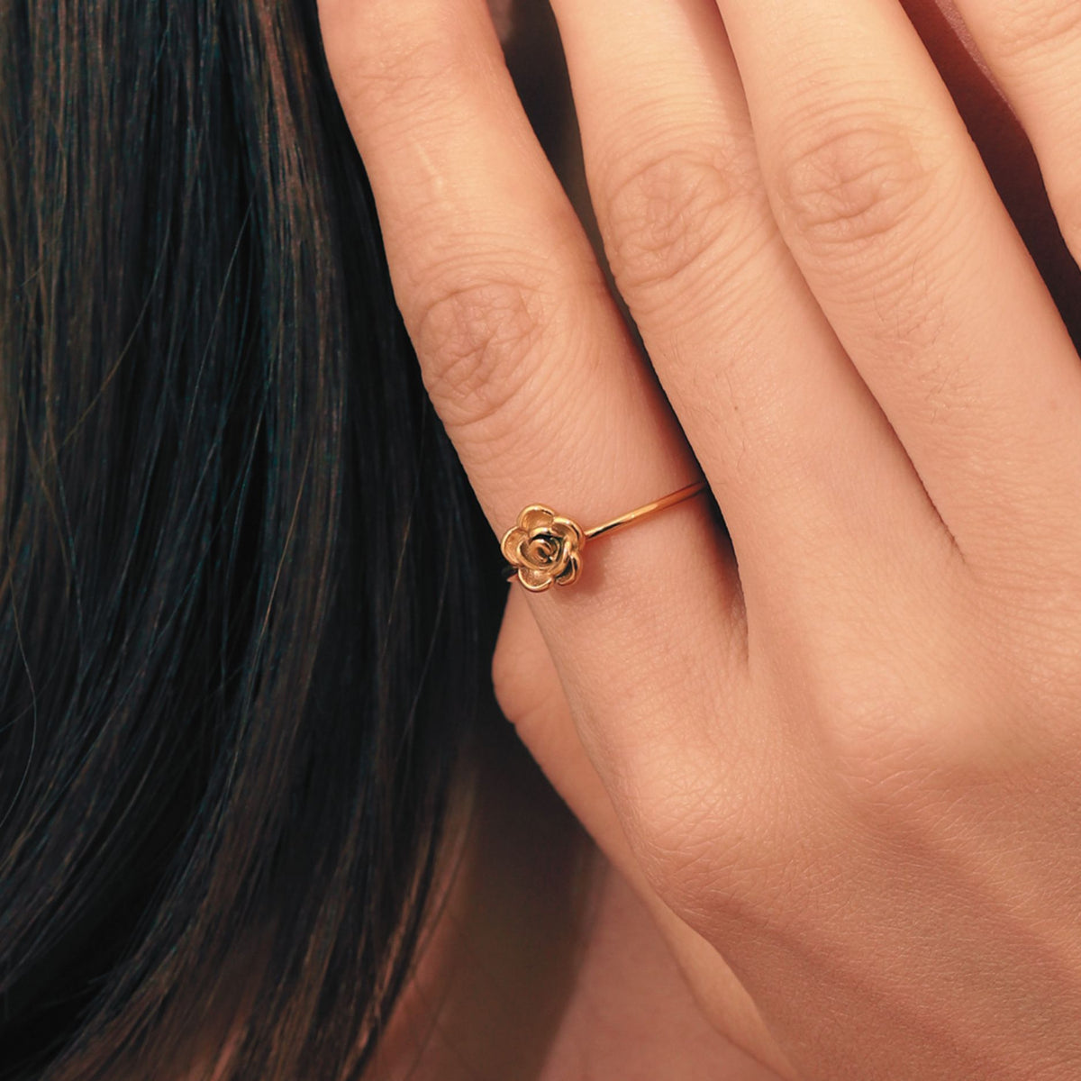 Woman wearing gold waterproof stainless steel rose bypass ring on index finger with minimalist dainty floral band