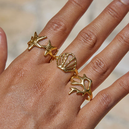 Model stacking three 18K gold-plated waterproof ocean rings including a starfish band, cutout seashell, and a coral branch design