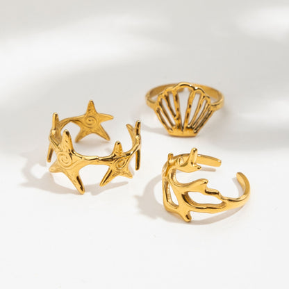 Set of gold rings with starfish, shell, and anchor designs on a white background