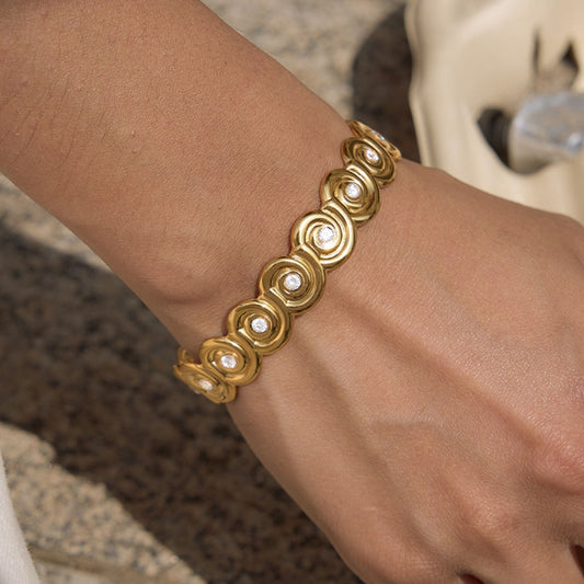 Model wearing a thick gold-plated waterproof nautilus wave cuff bracelet with embedded CZ crystals on a wrist