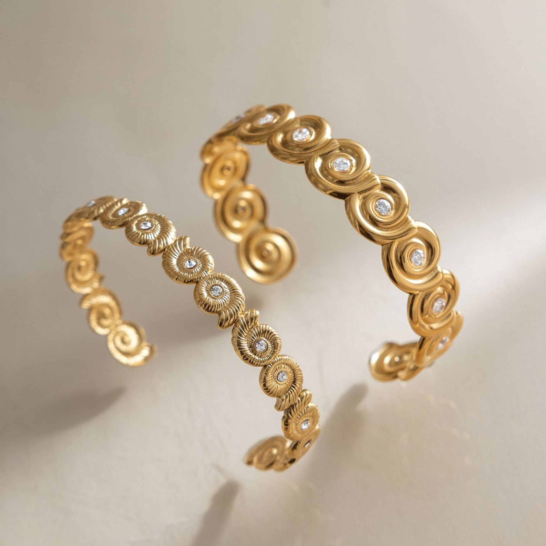 Two waterproof gold stainless steel ocean cuff bracelets in thick and thin styles showing the open adjustable back